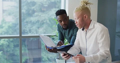 Diverse businessmen discussing with documents and tablet in creative office Stock Footage 336241453