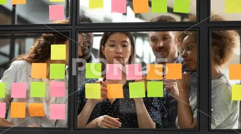 Diverse businesspeople discussing, planning project on sticky papers together Stock Photos