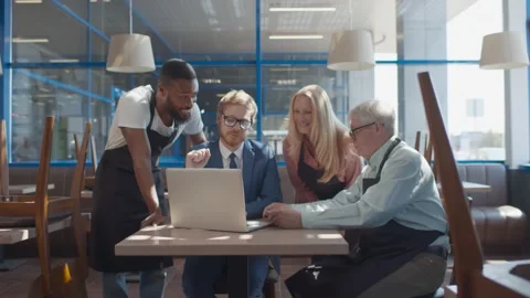 Diverse cafe waiters and manager discussing working schedule on laptop Stock Footage 135228200