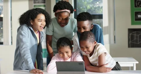 Diverse child students crowding seated peer using tablet in classroom reacting Stock Footage 337160046
