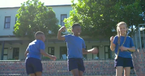 Diverse children in blue shirts starting waving arms together, jumping on school Stock Footage 342595953