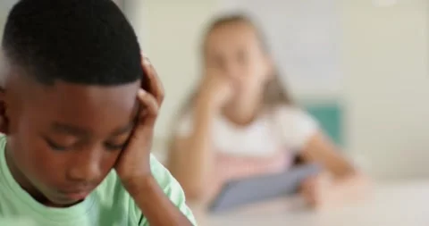 Diverse children in class, camera shifting focus, boy resting head, girl lifting Stock Footage 344326232