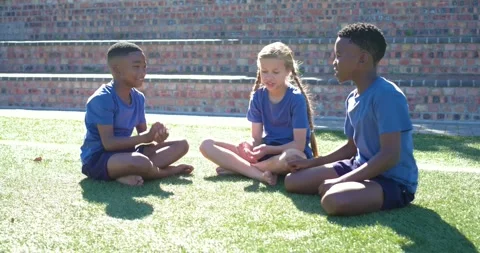 Diverse children exchanging hand gestures and starting clapping game on turf in Stock Footage 337537358