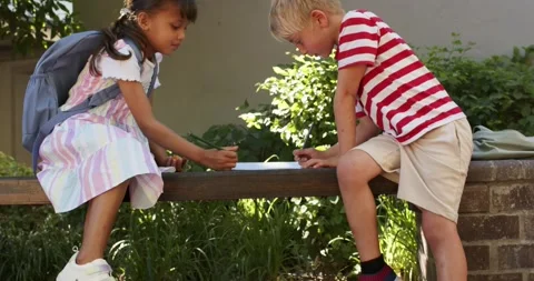 Diverse children sitting on bench in school paper lying in striped clothes Stock Footage 338167988