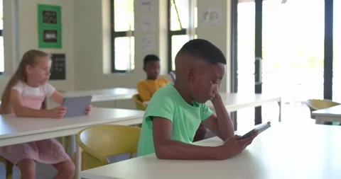 Diverse classmates in class using tablets, green-shirt boy leaning, peers Stock Footage 337705236