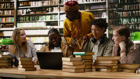 Diverse classmates in group study gather around laptop with study materials Stock Footage 337229809
