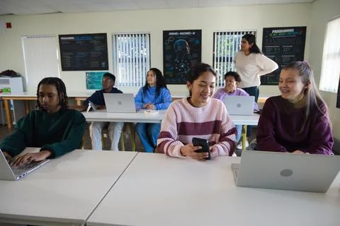 Diverse classmates using laptops and phone in computer lab with teacher Stock-Fotos