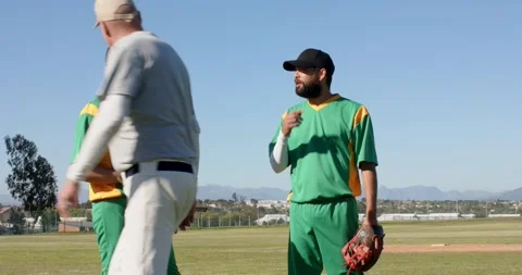 Diverse coach joining players on mound, gesturing field, showing baseball grip Stock Footage 342715926
