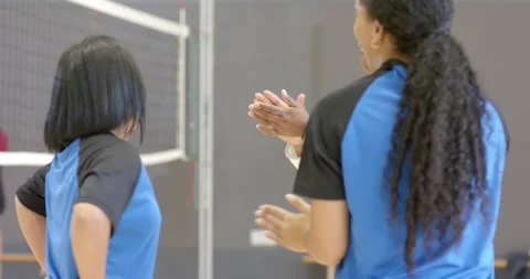 Diverse coach with players in jerseys raising hands and clapping drill at gym Stock Footage 335682956