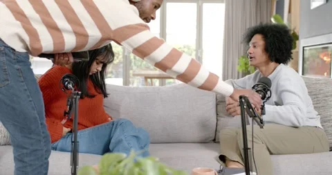 Diverse cohosts on couch while man with phone adjusting mic, starting chat, Stock Footage 345607706