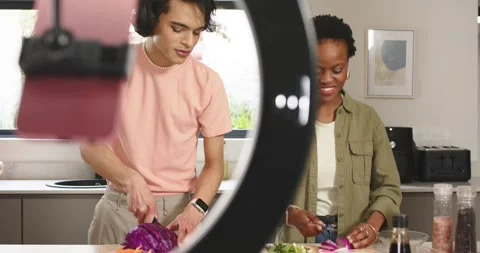 Diverse cohosts slicing cabbage and dicing onion in kitchen with ring light Stock Footage 340968959