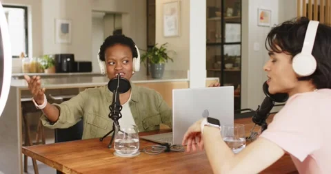Diverse cohosts speaking into microphone and listening with headset while Stock Footage 344383463