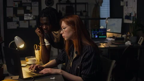 Diverse Colleagues Collaborating on Laptop in Dark Office at Night Stock Footage 338416905