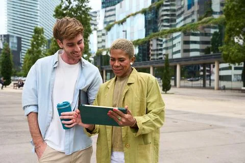 Diverse colleagues collaborating using digital tablet outdoors in city Stock Photos