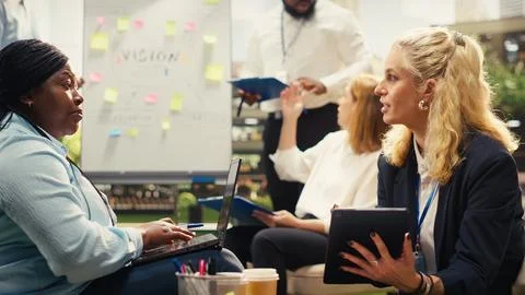 Diverse colleagues discuss action plan on laptop at outdoor work session Stock Photos