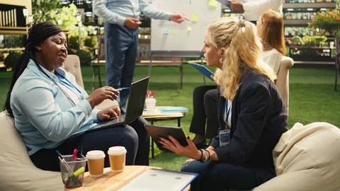 Diverse colleagues discuss action plan on laptop at outdoor work session Stock Photos