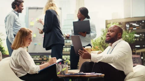 Diverse colleagues discuss planning notes beside laptop at outdoor meeting Stock Footage 338383371