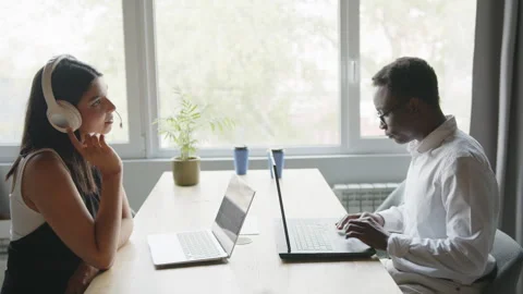 Diverse colleagues engage in a focused work session, a Black man typing on his Vidéo 335765178