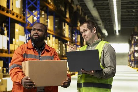 Diverse colleagues moving cargo in boxes using laptop for inventory control Foto stock