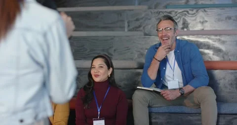 Diverse colleagues nodding, taking notes on benches while speaker using Stock Footage 317658989