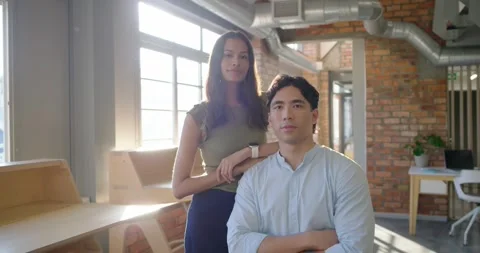 Diverse colleagues posing in loft office, woman resting arm, man crossing arms, Stock Footage 337944631