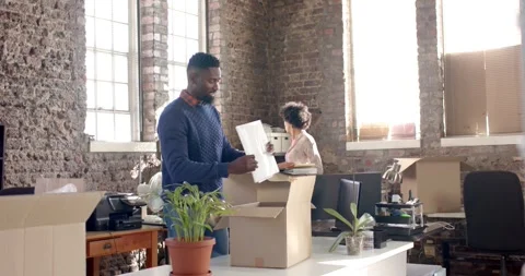 Diverse colleagues unpack office items and documents in creative setting, in Stock Footage 344330440