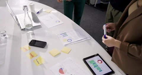 Diverse colleagues using charts annotating data and planning with peer joining 库存影片 336715292