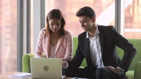 Diverse colleagues using laptop sitting on couch discussing business issues Stock Footage 131772098