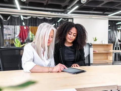 Diverse colleagues using tablet in modern workspace Stock Photos
