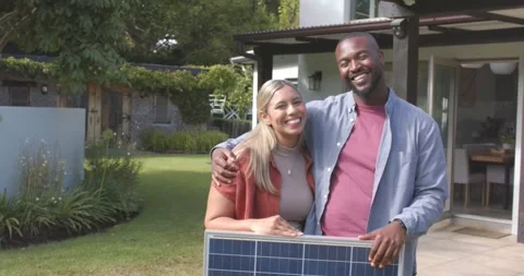 Diverse couple celebrating after installing solar panel while holding it in Stock Footage 335479583