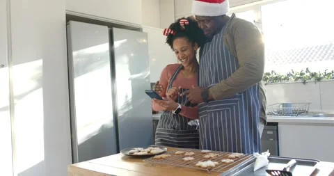 Diverse couple checking timer for cookies and guiding tapping on smartphone at Stock Footage 343366046