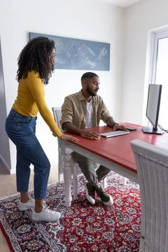 Diverse couple collaborating on desktop computer in home office corner with Stock Photos