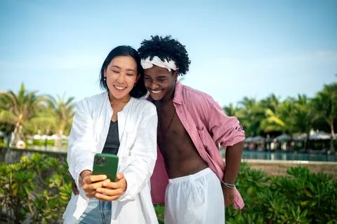 Diverse couple connected, embracing technology and social media while enjoy.. Stock Photos
