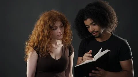 Diverse couple connecting while reading, sharing knowledge Stock Photos
