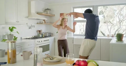 Diverse couple dancing, catching each other's eye, mirroring steps at kitchen Stock Footage 340882219