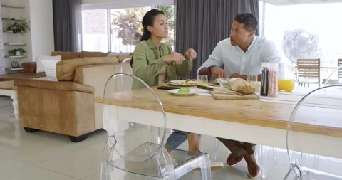 Diverse couple feeling hungry while slicing avocado and chatting at dining table Stock Footage 340610348