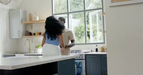 Diverse couple holding hands at kitchen island, dancing and pivoting while Stock Footage 340881873