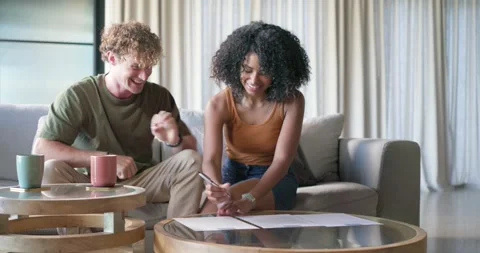 Diverse couple home noticing documents on table signing papers passing pen Stock Footage 344254465