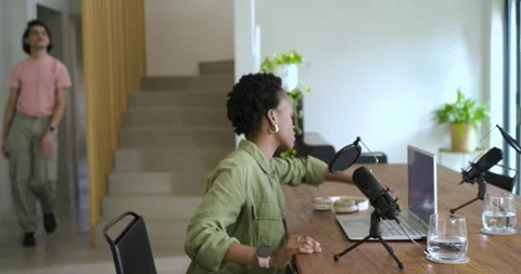Diverse couple hugging after adjusting podcast mics, guiding gaze around setup, Stock Footage 336844553