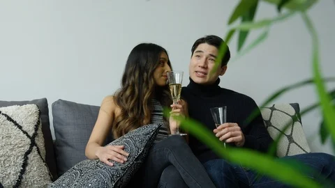Diverse couple interacting with each other while having champagne in living room Stock Footage 111968424