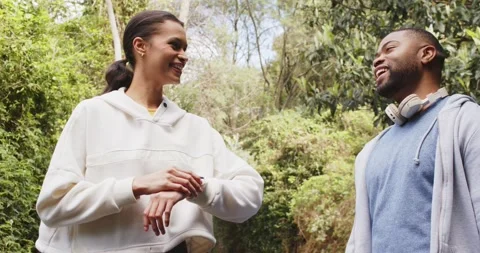 Diverse couple pausing on forest trail sharing wristwatch data, man wearing Stock Footage 336784102