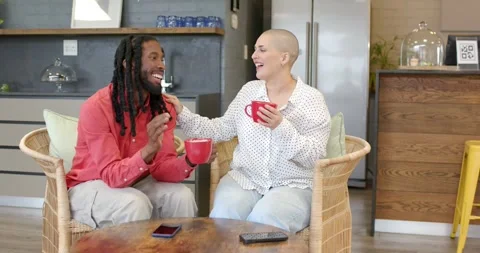 Diverse couple picking red mugs, settling at table in cafe, chatting over coffee Vídeo Stock 339272061