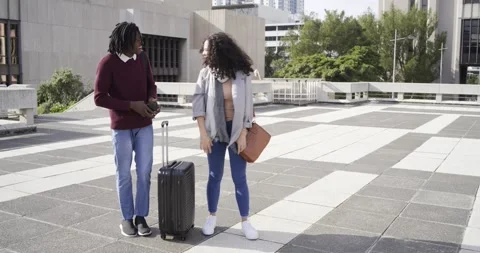 Diverse couple pointing to building, using phone map, planning route and rolling Stock Footage 339650992