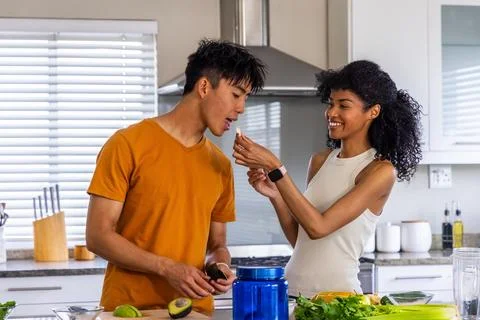Diverse couple preparing meal at kitchen counter, man holding avocado knife, Stock Photos