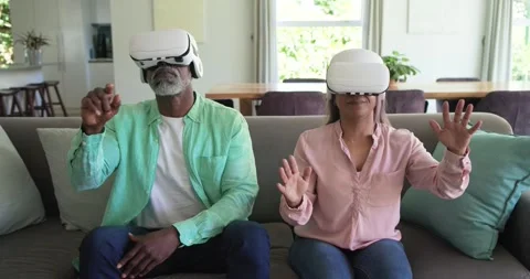 Diverse couple putting on white VR headsets, reaching and exploring virtual Stock Footage 339651650