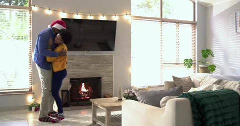 Diverse couple receiving holiday gift, dancing twirling by lit fireplace amid Stock Footage 320146887