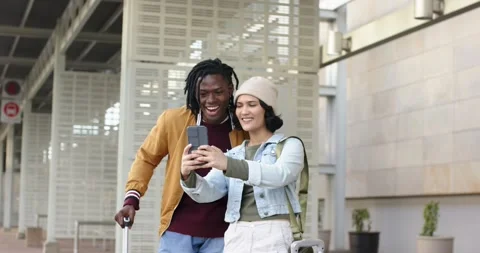 Diverse couple retrieving smartphone, posing and laughing while framing selfie Stock Footage 317788349