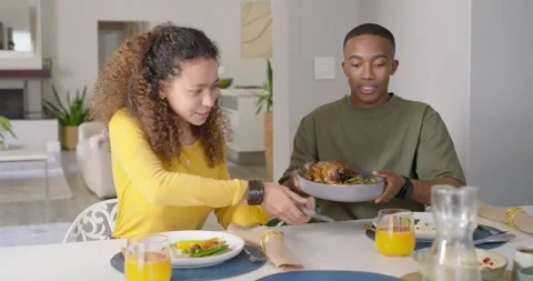 Diverse couple serving dinner, man reaching lifting roast bowl, carving chicken Stock Footage 337286384