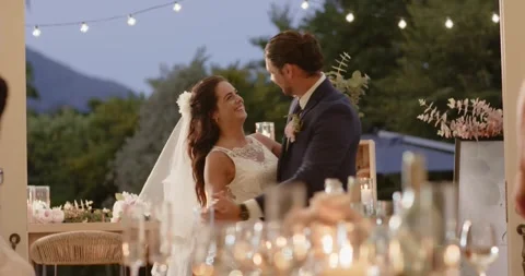 Diverse couple sharing first dance on patio raising arm twirling bride dipping Stockbeeldmateriaal 316688498