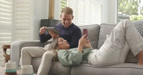 Diverse couple sharing pink phone, woman scrolling to show phone, man glancing Stock Footage 337933478